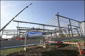 Workers with Henry Gurtzweiler Inc., install roof trusses for the new Cutting Edge Countertops factory expansion in Perrysburg. The company, which cuts and sells counters of natural stone and other materials, will be expanding its production area and creating a larger, 