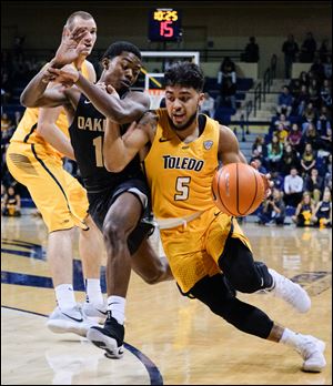 Toledo's Justin Roberts drives past Oakland's Brailen Neely during Toledo's 87-74 win Saturday at Savage Arena.