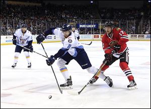 Toledo's Christian Hilbrich, left, chases the puck as Indy's Andrew Schmit defends Saturday at the Huntington Center. Toledo won the game, 3-2.