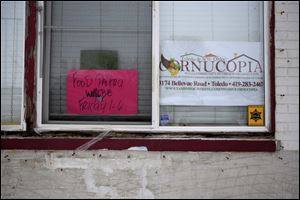 Signs in the window at the Toledo & Northwest Ohio Cornucopia food and clothing pantry in Toledo on Friday, Dec. 29. The pantry's trailer that played a large role in their operations was recently stolen, limiting how much they can bring into the pantry.