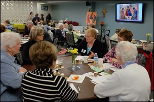 Lisa Strugarek, hands up and facing camera, speaking with a group of women religious and associates. 