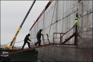 Workers enter through a doorway cut into the hull of one of the several Great Lakes freighters docked for repairs and modifications. About a dozen large cargo freighters are docked at the company's yard to undergo repairs while the Great Lakes remain covered in ice. The shipping seasons ends the day the Soo Locks close for the winter. 