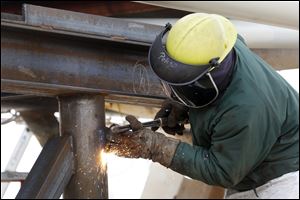 A worker welds on the boom crane of the Great Lakes freighter the John J. Boland as she is docked alongside other Great Lakes freighters for repairs and modifications.