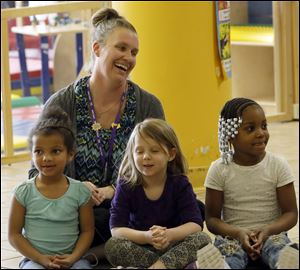 Heather Davis-Harris, center, sits with several of her students at Toledo Public Schools Head Start on Wednesday, April 11 in North Toledo. Volunteers from PNC Bank dropped off 1,000 book bags for preschoolers before holding a ceremony to award one teacher, Ms. Davis-Harris, with two $2,000 gift cards to help with supplies for her classroom. 