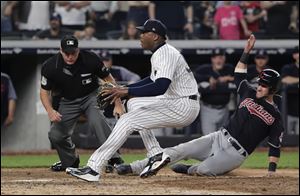 Cleveland Indians' Yan Gomes scores on a wild pitch by New York Yankees pitcher Aroldis Chapman, left, during the ninth inning.