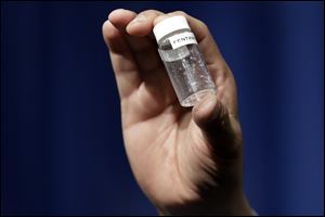 A man holds up an example of the amount of fentanyl that can be deadly after a news conference about deaths from fentanyl exposure.