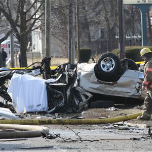 A fireman walks past one of two vehicles involved in a fatal crash in the 2100 block of West Alexis Road.