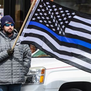 A man holds a thin blue lives flag during the funeral procession for fallen Bluffton police officer Dominic Francis in Bluffton on April 8. (THE BLADE/REBECCA BENSON)